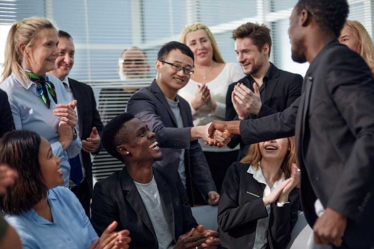 Two people shaking hands in a group meeting