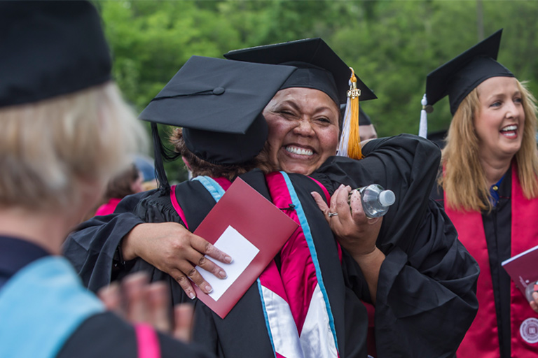 A female graduate gives another a bear hug