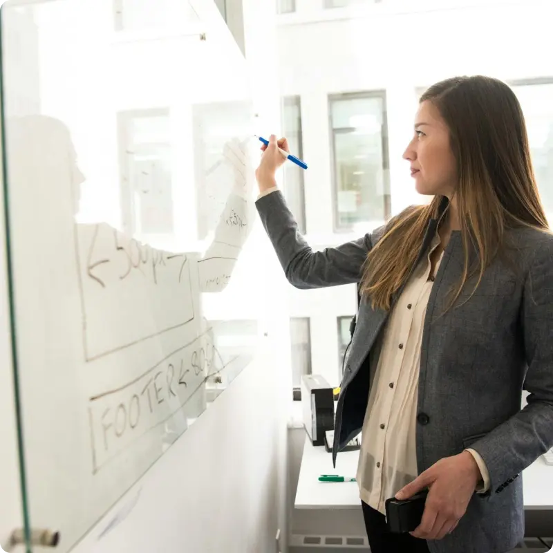 Woman standing and writing on a dry erase board