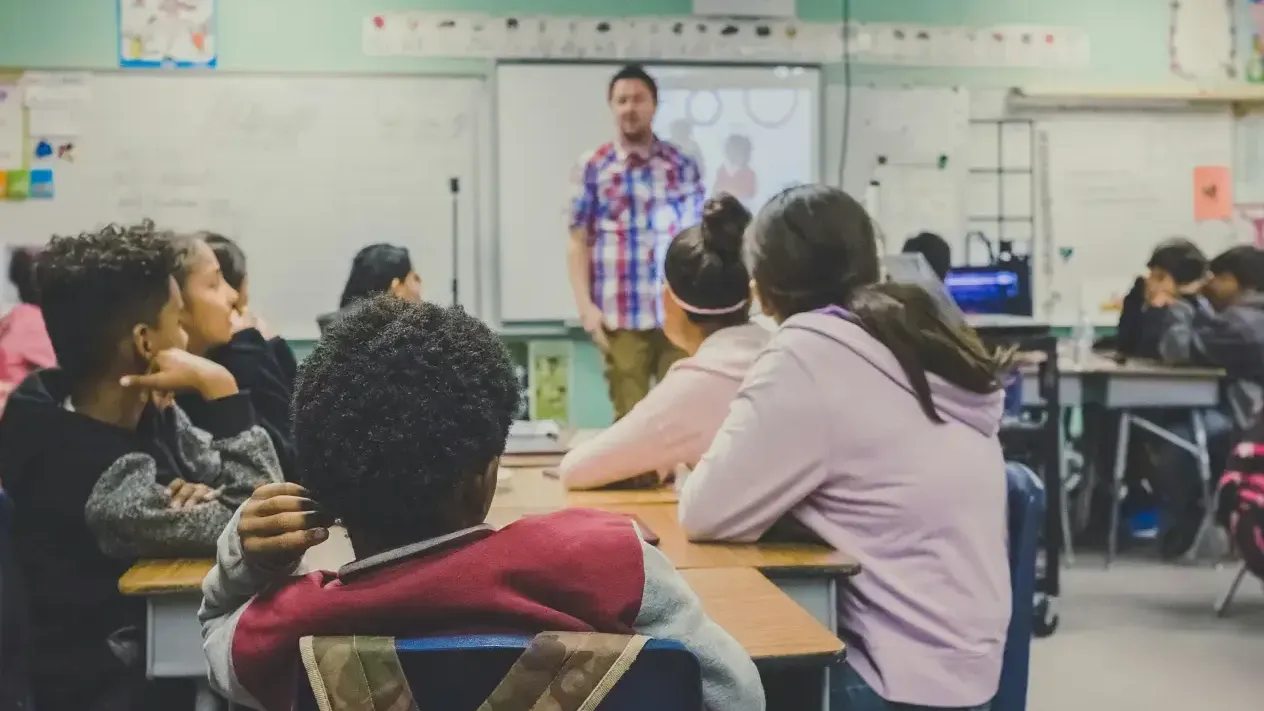 Man standing in front of a classroom talking to young students