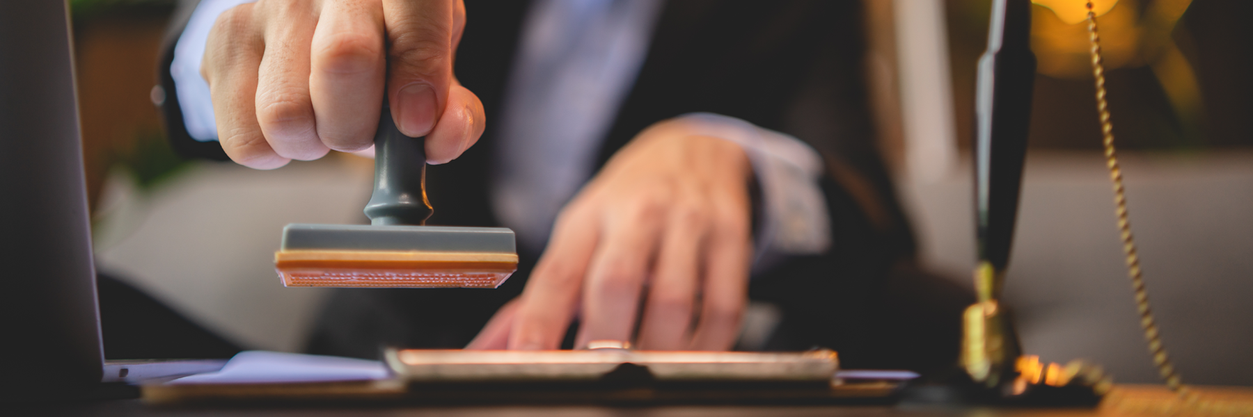 Close-up of two hands, with one of them rubber-stamping a pile of papers.