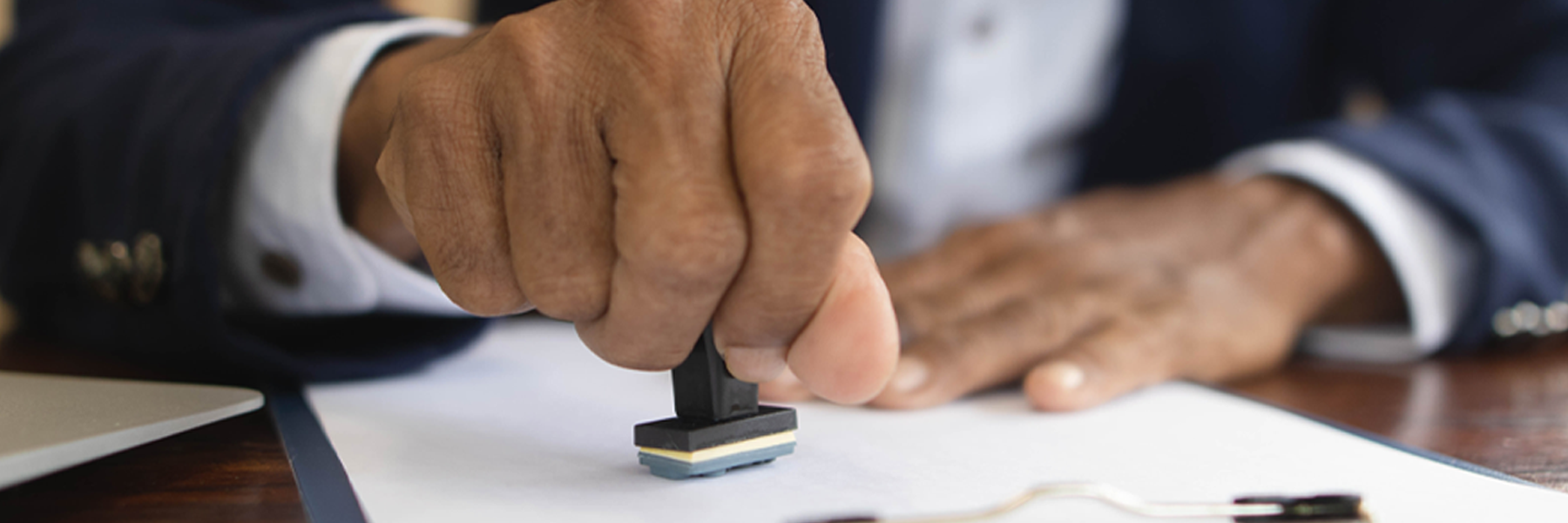 Close-up of a hand rubber-stamping a stack of documents.