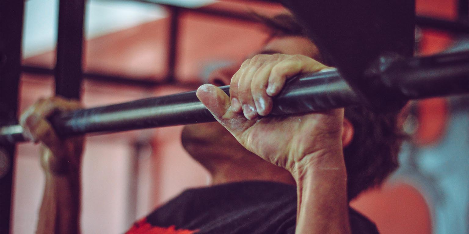 Male student doing a pull up in fitness center